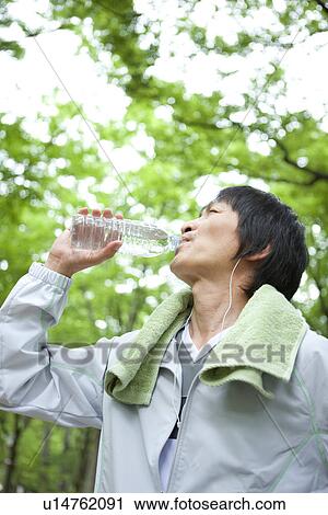 Mature man listening to music and drinking water View Large Photo Image Stock Image - Mature man listening to music and drinking water. Fotosearch