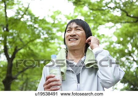 Mature man listening to music and holding water bottle View Large Photo Image Stock Image - Mature man listening to music and holding water bottle. Fotosearch