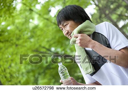 Mature man rubbing sweat and holding water bottle View Large Photo Image Stock Photo - Mature man rubbing sweat and holding water bottle. Fotosearch