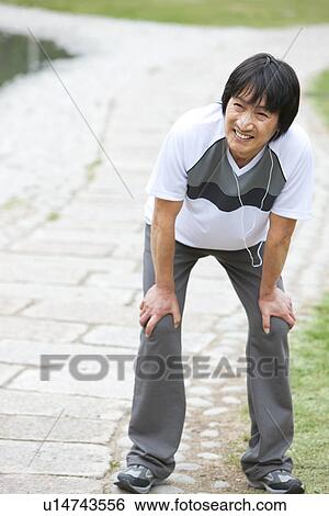 Stock Photograph - Mature man taking a break from jogging. Fotosearch
