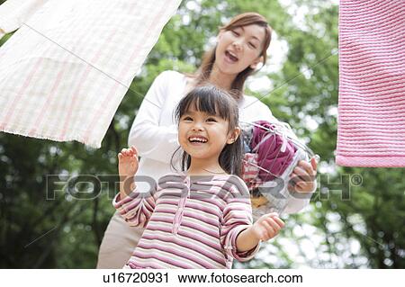 Stock Image - Mother and daughter doing laundry. Fotosearch