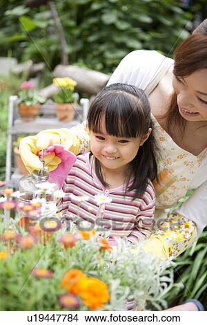 Picture - Mother and daughter spraying water on potted flower. Fotosearch