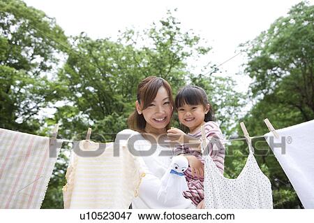 Mother and daughter standing behind clothesline and holding teru teru bozu View Large Photo Image Stock Photo - Mother and daughter standing behind clothesline and holding teru teru bozu. Fotosearch