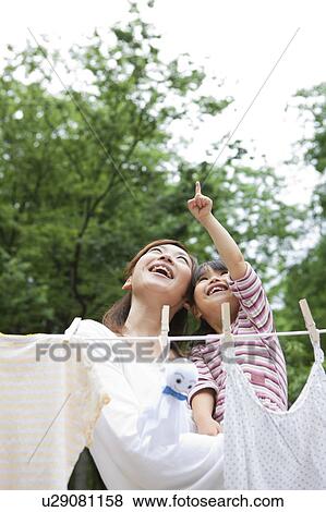 Stock Photo - Mother and daughter standing behind clothesline and holding teru teru bozu. Fotosearch