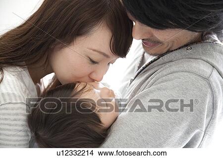 Picture - Mother Kissing Baby Boy Who Sleeps in Father's Arms. Fotosearch