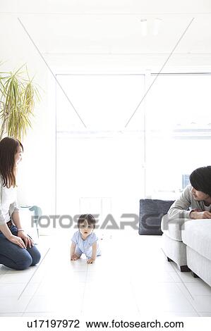 Stock Image - Parents Watching Baby Boy Crawling. Fotosearch