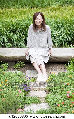 Stock Photography - Portrait of young woman sitting on bench. Fotosearch