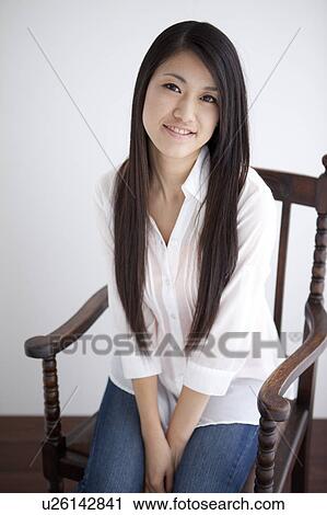 Portrait of young woman sitting on chair View Large Photo Image Stock Image - Portrait of young woman sitting on chair. Fotosearch