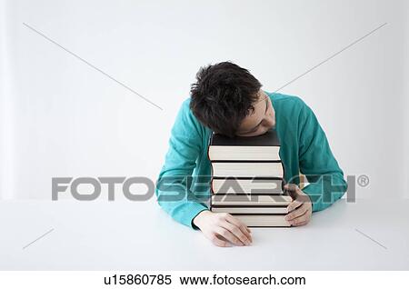 Stock Photography - Young man falling asleep while studying. Fotosearch