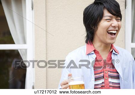 Young man holding a mug of beer View Large Photo Image Stock Image - Young man holding a mug of beer. Fotosearch