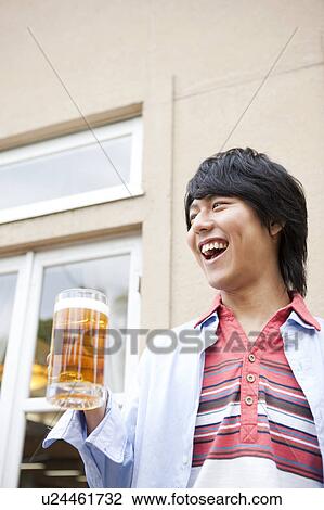 Young man holding a mug of beer View Large Photo Image Stock Image - Young man holding a mug of beer. Fotosearch