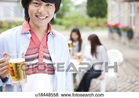 Young man holding a mug of beer View Large Photo Image Stock Photo - Young man holding a mug of beer. Fotosearch