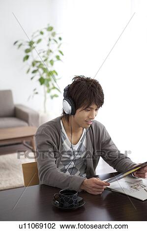 Young man listening to music and holding a record View Large Photo Image Stock Image - Young man listening to music and holding a record. Fotosearch