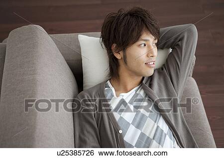 Young man lying on sofa smiling View Large Photo Image Stock Photograph - Young man lying on sofa smiling. Fotosearch