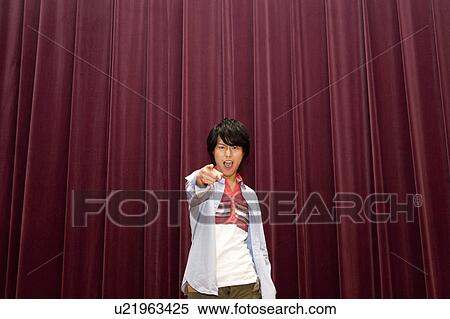 Stock Photography - Young man on stage pointing at camera. Fotosearch