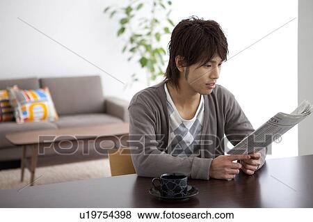Young man reading a newspaper View Large Photo Image Stock Photo - Young man reading a newspaper. Fotosearch