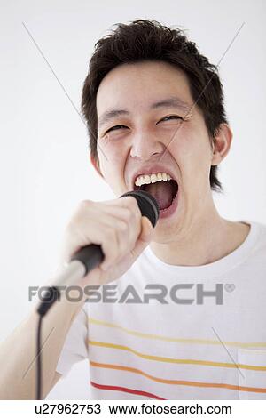 Stock Image - Young man singing into microphone. Fotosearch