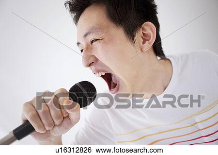 Stock Photograph - Young man singing into microphone. Fotosearch