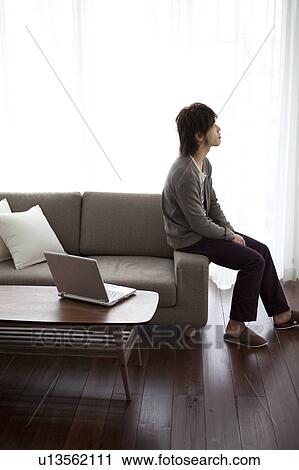 Young man sitting on sofa looking up View Large Photo Image Stock Image - Young man sitting on sofa looking up. Fotosearch