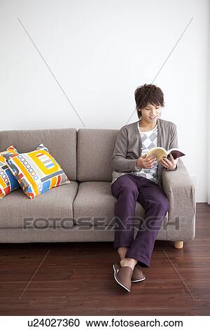 Young man sitting on sofa reading a book View Large Photo Image Stock Image - Young man sitting on sofa reading a book. Fotosearch