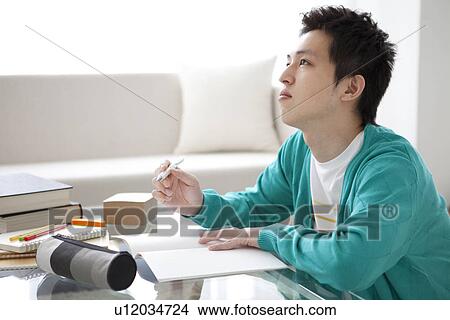 Young man studying at table View Large Photo Image Picture - Young man studying at table. Fotosearch
