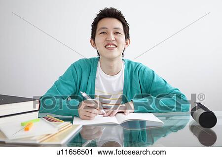 Young man studying at table View Large Photo Image Stock Image - Young man studying at table. Fotosearch