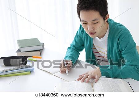 Stock Image - Young man studying at table. Fotosearch