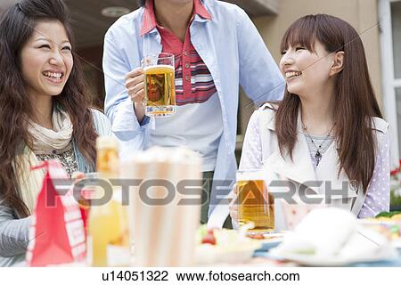 Stock Image - Young people drinking beer outdoors. Fotosearch
