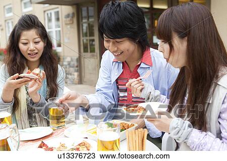 Stock Image - Young people eating at an outdoor cafe. Fotosearch