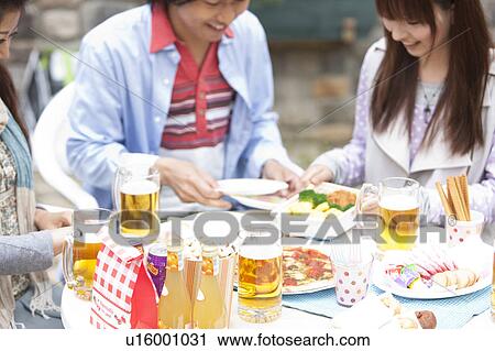 Stock Image - Young people eating at an outdoor cafe. Fotosearch