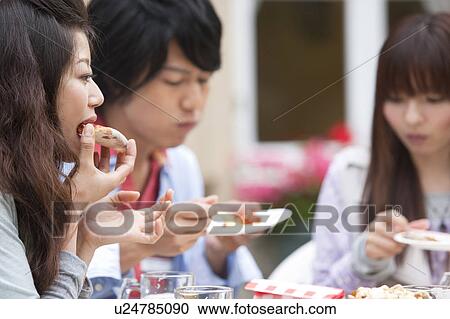 Stock Image - Young people eating at an outdoor cafe. Fotosearch