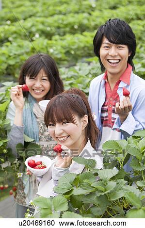 Stock Image - Young people holding strawberries. Fotosearch