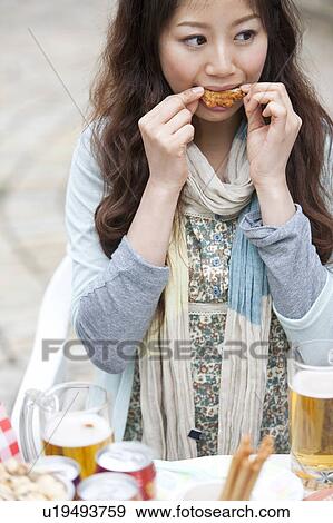Stock Photo - Young woman eating at an outdoor cafe. Fotosearch