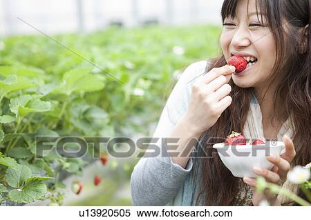 Stock Photography - Young woman eating strawberry. Fotosearch