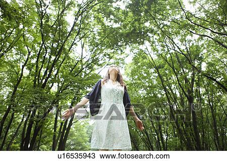 Stock Image - Young Woman Enjoying Herself in Forest, Low Angle View. Fotosearch