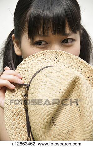 Stock Image - Young Woman Hiding Behidn Hat. Fotosearch