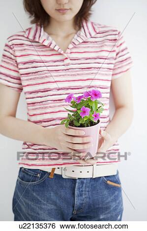 Stock Photograph - Young woman holding potted flower. Fotosearch