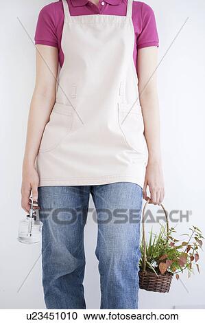Young woman holding spray bottle and potted plant View Large Photo Image Stock Image - Young woman holding spray bottle and potted plant. Fotosearch