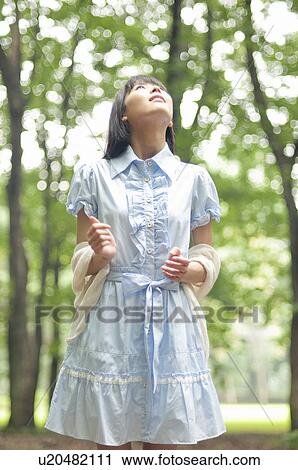 Stock Image - Young Woman Looking Up in Forest. Fotosearch