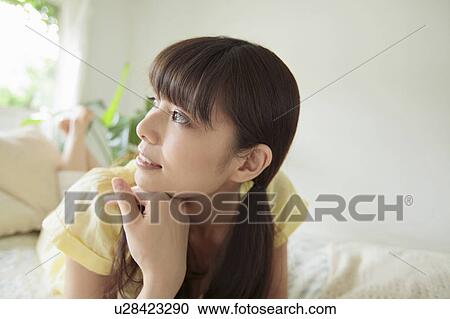Stock Image - Young Woman Lying on Bed. Fotosearch