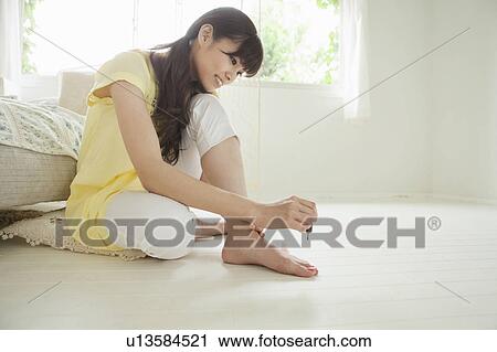 Stock Image - Young Woman Painting Her Toenails. Fotosearch