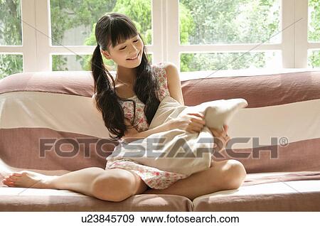 Stock Photo - Young Woman Sitting on Sofa. Fotosearch