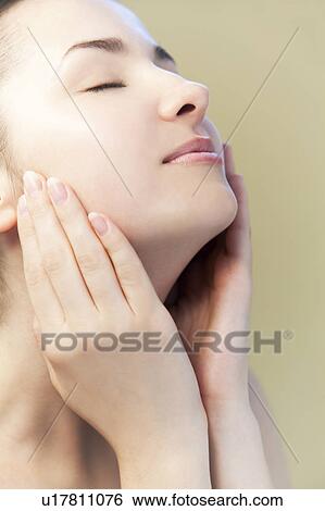 Young woman touching face View Large Photo Image Stock Photograph - Young woman touching face. Fotosearch