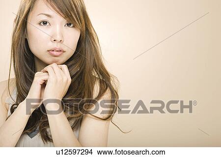 Picture - Young woman with hand on chin. Fotosearch