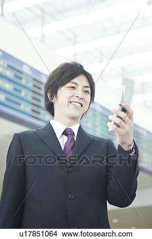 Picture - A businessman holding mobile phone. Fotosearch