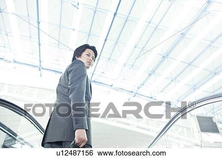 A businessman taking the escalator View Large Photo Image Stock Photograph - A businessman taking the escalator. Fotosearch