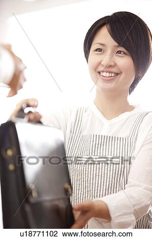 Stock Image - A woman handing a bag. Fotosearch