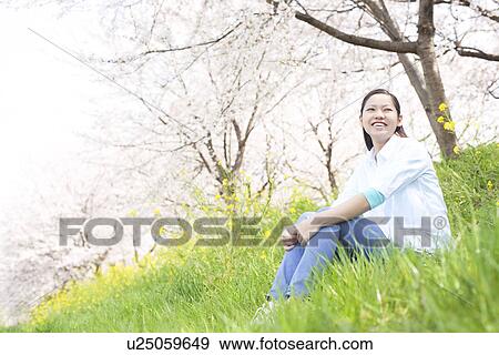 Stock Photo - A young woman sitting on the bank. Fotosearch