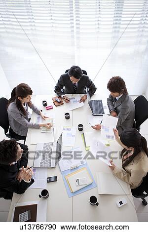Businesspeople having a meeting, high angle view View Large Photo Image Stock Image - Businesspeople having a meeting, high angle view. Fotosearch