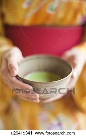 Stock Image - Close Up of Woman Holding Cup of Powdered Tea. Fotosearch